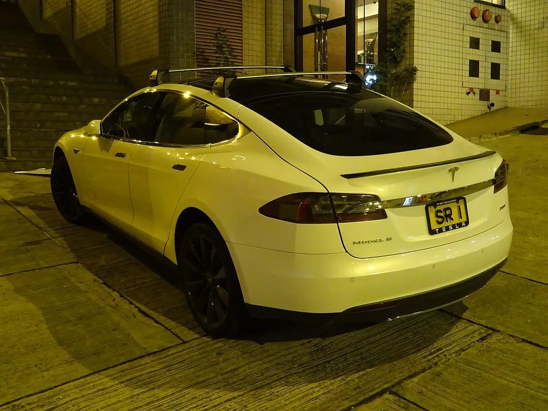 Tesla Model S blanco aparcado de noche en una calle de Hong Kong, otro ángulo