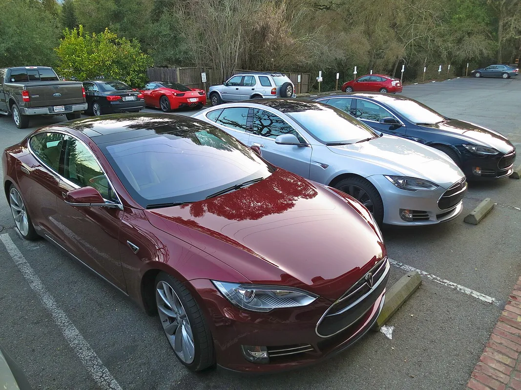 Tres Tesla Model S (rojo, blanco y azul) aparcados en un parking
